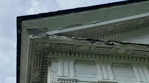 The Gatton Trust A historical building with damaged wooden features.