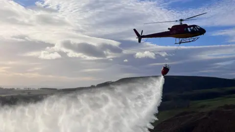 A helicopter demonstrates water bombing on a moorland in Aberdeenshire
