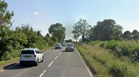 Google Cars on a two lane road with trees and hedges on either side. 
