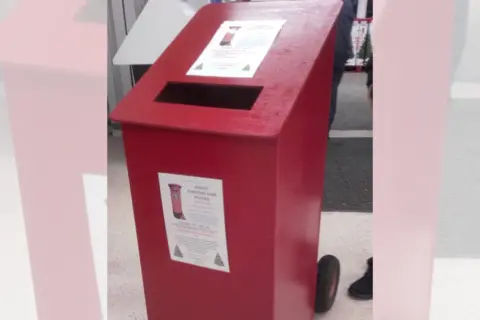 Wayne Bavin/BBC A red wooden post box placed inside somewhere. It has a couple of posters printed on it.