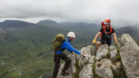 The Outward Bound Trust Two young people crest the summit of a mountain in Snowdonia