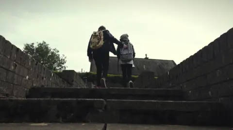 Edward Ryan Two young people with backpacks walk up a set of stairs