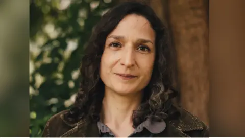 Headshot of Angela Tomaski smiling outside in front of a tree.