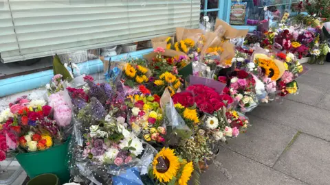 Dozens of bouquets left on a pavement outside a pet shop in Wiltshire.