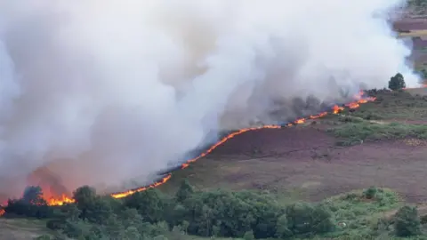 Aerial shot of heathland with flames showing in a line.