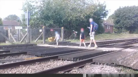 An unknown family crossing a train track