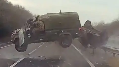 Land Rover and trailer roll through the air on an A-road.