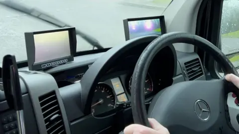 Driver's position in a vehicle with two video screens above the steering wheel