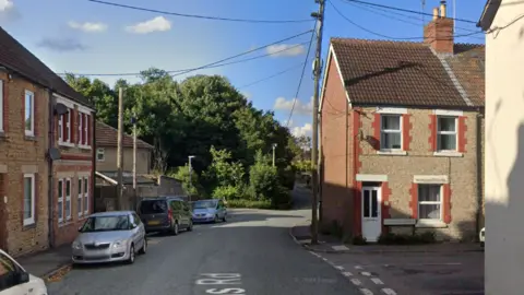 Woodlands Road in Chippenham. It is a residential street with terraced houses. Cars align the image on the left.