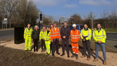 Wiltshire Council People stood in a group smiling with a road and traffic lights behind them