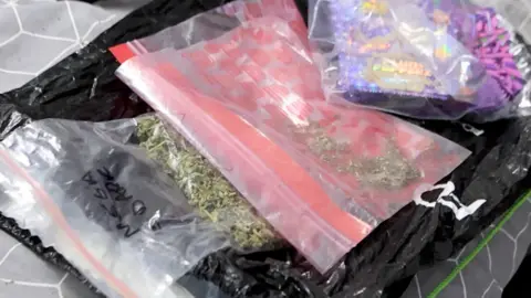Greater Manchester Police Photograph of illegal drugs which have been seized by Greater Manchester Police. The image shows the drugs inside small plastic bags.
