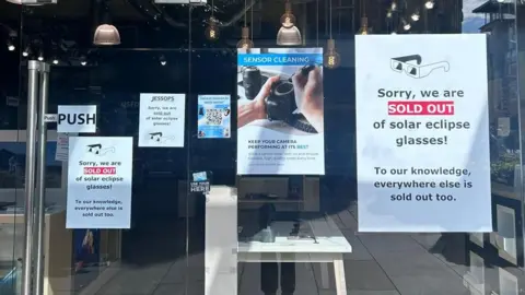 Signs in a shop window which read: "Sorry, we are SOLD OUT of solar eclipse glasses! To our knowledge, everywhere else is sold out too."