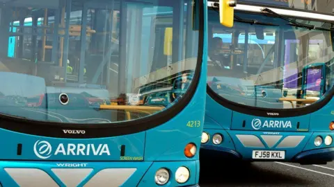 PA Media Two cyan single-decker buses parked side by side, facing the camera. The word Arriva is written under the windscreen on both buses.