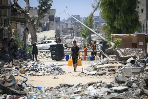Getty Images A boy walks through rubble in Gaza