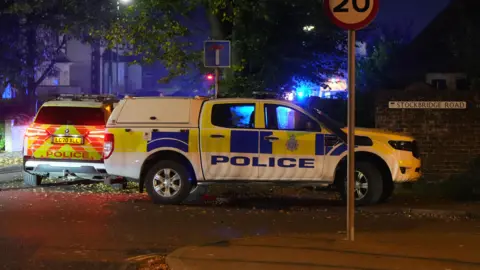 Two police cars parked on the side of the road at night.