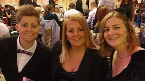 The Royal Wolverhampton NHS Trust Nobi, with short hair, in a black blazer and a bow tie, Sam, in a black jacket and blouse and Cheryl, in black, wearing a hair piece 