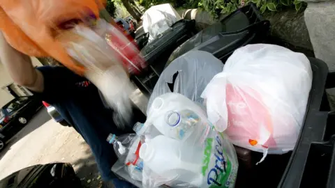 PA Media Man empties waste into a bin