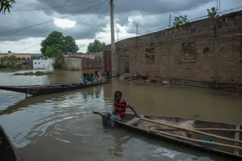 OUSMANE MAKAVELI / AFP Boys sit on pirogues in the flooded area of the Kalaban Koro district in Bamako - Wednesday 2 October 2024