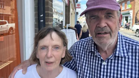 Ben Parker/BBC A man and a woman looking at the camera, the man has a red hat and blue shirt on, the woman is wearing a white top.