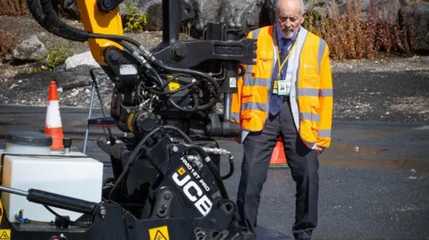 Leicestershire County Council A man in a high-vis coat looks at a JCB machine 