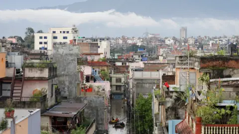 Reddingsteams van Reuters brengen bewoners naar een veilige plek vanuit een overstroomd gebied nabij de oever van de Bagmati-rivier, die overstroomt na zware regenval in Kathmandu.