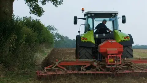 Getty Images/Henry Arden Farmer driving tractor
