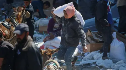 Reuters A Palestinian boy carries a bag with aid supply provided by the UN's Palestinian refugee agency (Unrwa) in northern Gaza Strip. Photo: 2 March 2025