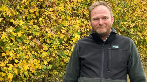 George Brown Farmer George Brown looking at the camera. There are trees behind him.