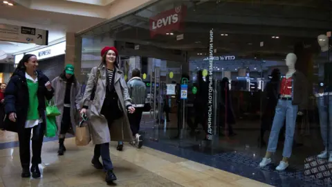 Getty Images Shoppers walk by a shuttered Levi's store in Moscow