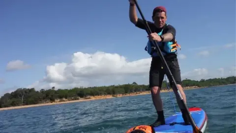 Roy Beal Joe Cartwright on a paddleboard