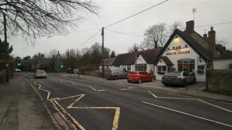 Road through a village with a white pub on the right