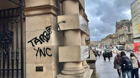 There is black graffiti on the sandstone building.