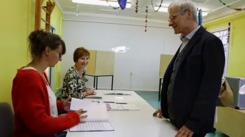 Reuters Man at polling station speaks to two female election officials