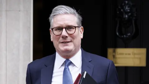 EPA-EFE/REX/Shutterstock Sir Keir Starmer outside 10 Downing Street on his way to Prime Minister's Questions. He is carrying two folders under his arm and is wearing a smart suit, with a blue tie.