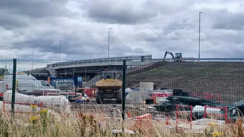 Northumberland County Council Construction work is happening at a railway station on a new road bridge. 