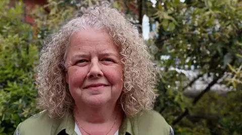 Clare Down, one of the women who was given a fast MRI scan during a trial in North Bristol which picked up a cancerous tumour. She is wearing a green blouse and has blonde hair.