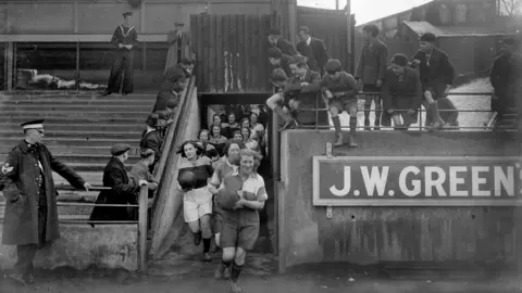 Luton News Photo of a ladies' football team running out onto the Luton Town pitch in 1935.