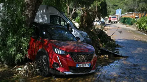 Damaged vehicles on a mud-covered street following a flood caused by heavy rain in Le Lavandou 