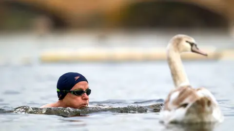 PA Media Man swimming in a river