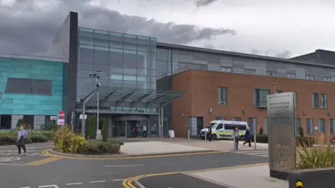 The Northern Centre for Cancer Care at the Freeman Hospital. The building has a red-brick section to the right. The main entrance is in the middle and is made predominantly from glass.