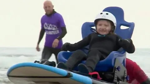 Child surfing in a specially-adapted surfboard with a seat