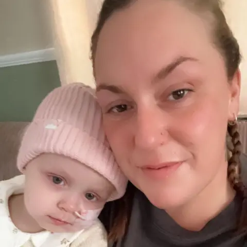 Supplied A small child wearing a pink hat posing for a picture with her mum