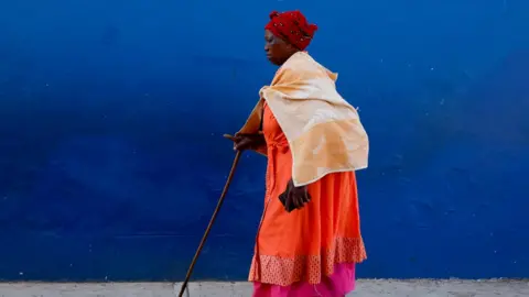 Rogan Ward/Reuters A woman walks, on the day of the South African elections in Nkandla, South Africa, May 29, 2024.