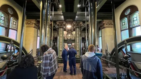An engine pumping room, with engineers and people milling around. 
