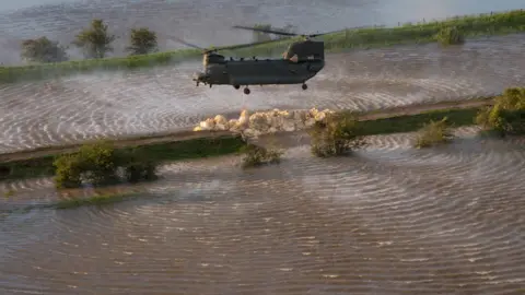 EPA RAF Chinook helicopter dropping ballast on the breach in the River Steeping