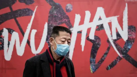 Getty Images A man wears a mask while walking in the street on 22 January 2020 in Wuhan