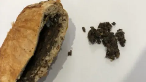 Supreme Court of Victoria A zoomed in picture of a beef wellington that has been cut open. You can see the filling inside and some of the filling has been placed on the table next to it. It's brown and mushy