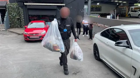 An HMRC officer carries two sacks of evidence
