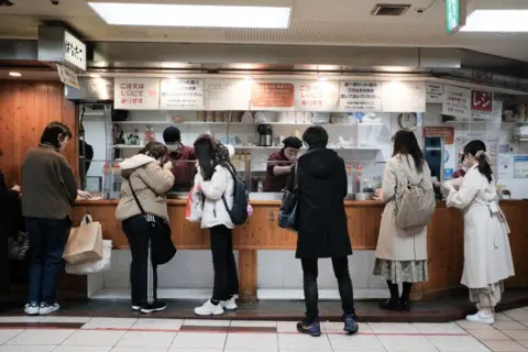 I clienti ordinano il takoyaki in un negozio di Osaka, in Giappone, nel 2023