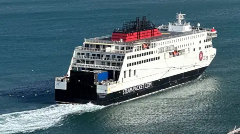 The Manxman ferry sails out of Douglas Harbour on a sunny day with calm blue seas.